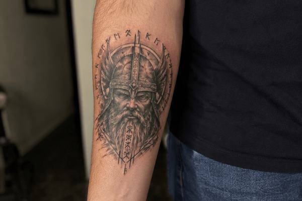 Wikingerkopf-Tattoo mit Runen am Unterarm