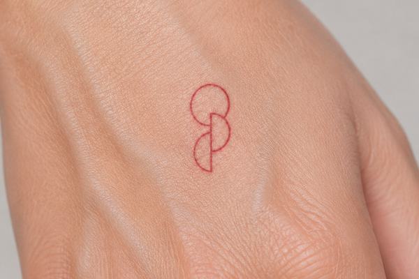 Kleines, rotes Fineline-Tattoo auf dem Handrücken