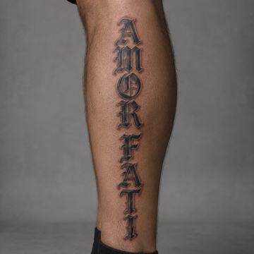 Unterschenkel mit großem, vertikal gesetztem „AMOR FATI“-Tattoo