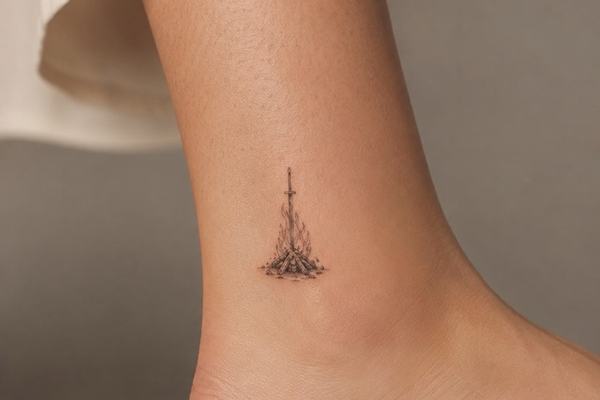 Kleines Dark-Souls-Bonfire-Tattoo in Schwarz‑Grau am Knöchel