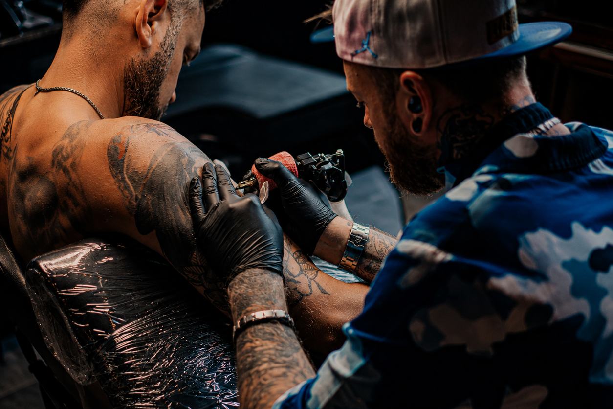Tätowierer arbeitet an einem Schulter-Tattoo