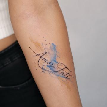 Unterarmtattoo mit feinem, kursiven „Amor Fati“-Schriftzug