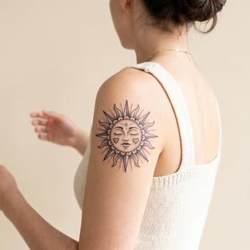 Sonnen-Tattoo mit Gesicht am Oberarm