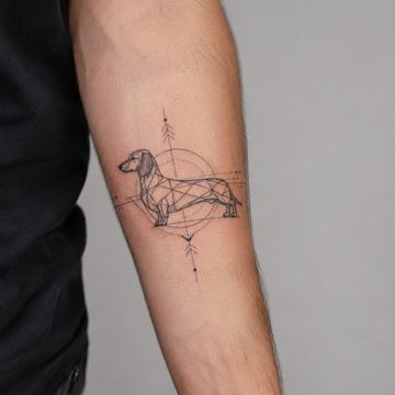 Geometrisches Fineline‑Dackel‑Tattoo in Schwarz‑Grau auf dem inneren Unterarm
