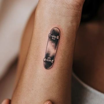 Kleines, fein schattiertes Skateboard‑Tattoo 