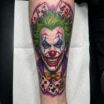 Großflächiges, farbiges Joker-Porträt als realistisches Tattoo am Unterschenkel