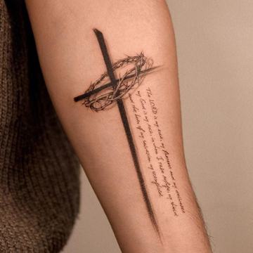 Kreuz-Tattoo mit Schriftzug am Unterarm
